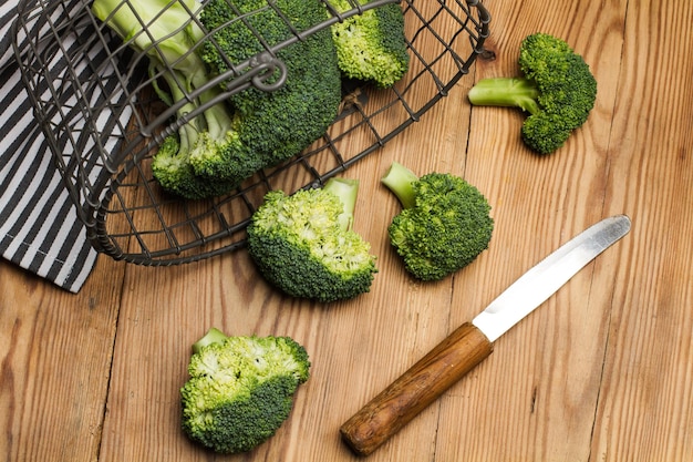 Broccoli in una cesta di filo metallico e su un tavolo di legno