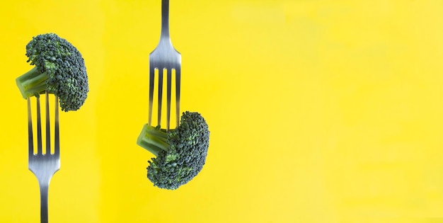 Broccoli pugnalati su una forchetta d'argento sullo sfondo giallo Closeup Copia spazio