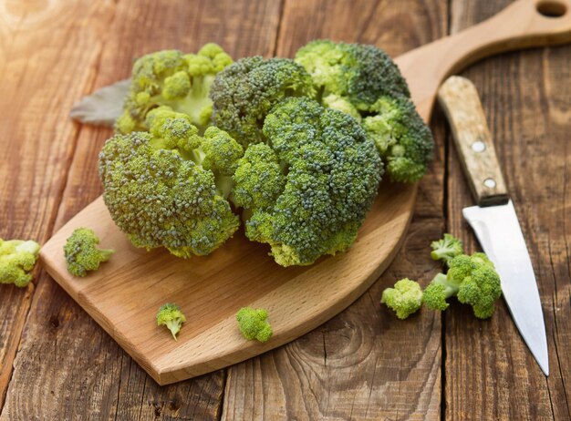 Broccoli verdi freschi su un tagliere di legno con un coltello Foglie di cavolo broccoli