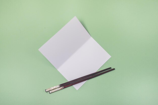 Brochure di carta bianca con bastoncini di cibo su sfondo verde chiaro Mock up con carta bianca in bianco orizzontale