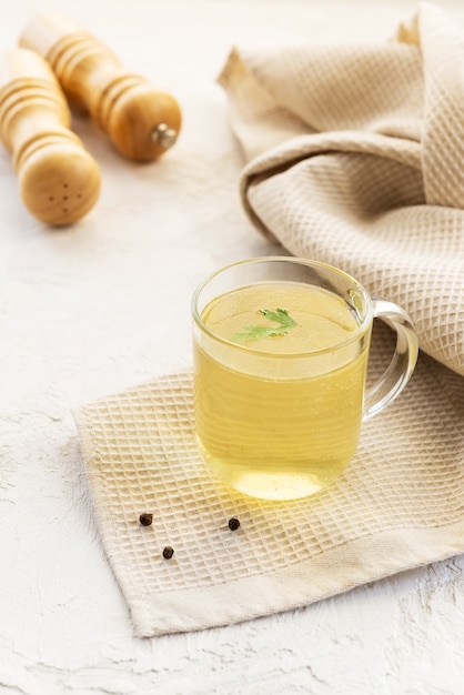 Brodo di ossa di pollo in una tazza di vetro sul tavolo