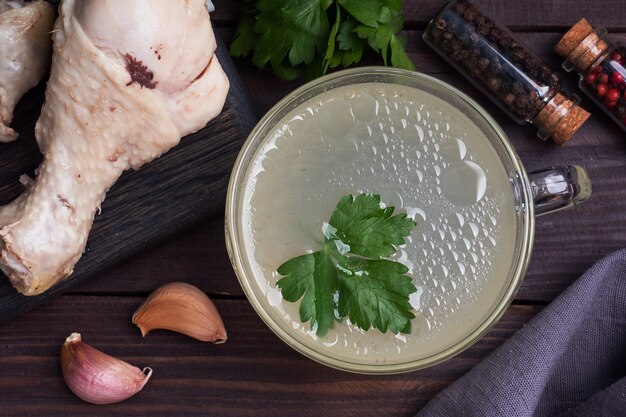 Brodo di pollo in una tazza di vetro. Quarti di coscia di pollo bolliti.