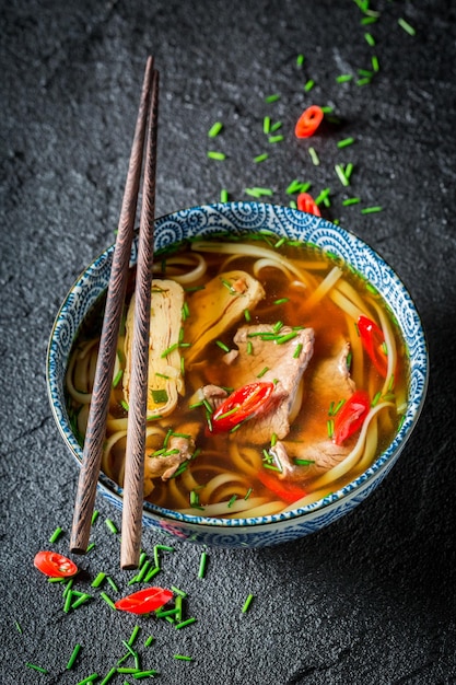 Brodo tailandese caldo con carne di manzo e noodle su roccia nera