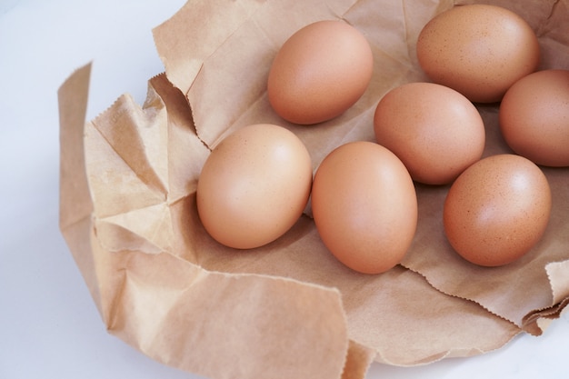 Brown uovo in sacchetto di carta dietro su uno sfondo di colore chiaro, uova di gallina fresche sulla tavola di legno