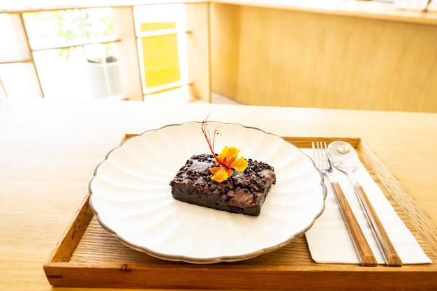 Brownies fatti in casa con gocce di cioccolato su un piatto bianco cucchiaio e forchetta su uno sfondo di legno