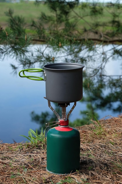 Bruciatore a gas da campeggio con pentola sulla costa del fiume