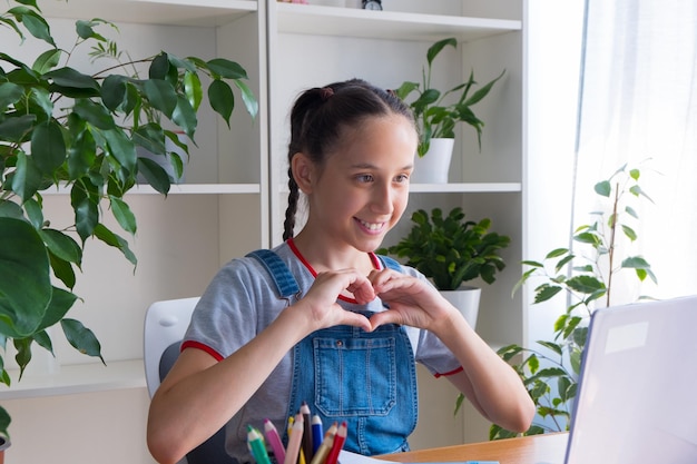 Bruna anni vestita con una maglietta grigia seduta a casa a studiare scrivendo i compiti parlando al