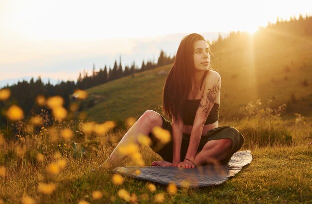 Bruna carina si siede sul tappetino da yoga Maestose montagne dei Carpazi Bellissimo paesaggio di natura incontaminata