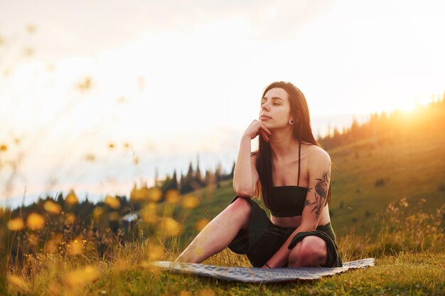 Bruna carina si siede sul tappetino da yoga Maestose montagne dei Carpazi Bellissimo paesaggio di natura incontaminata