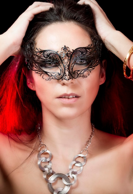 Bruna con maschera veneziana. Gioielli e bellezza. foto di moda