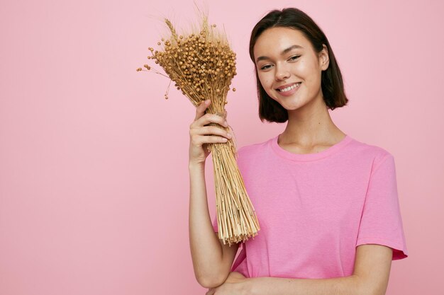 Bruna dai capelli corti un bouquet di fiori secchi maglietta rosa Stile di vita inalterato