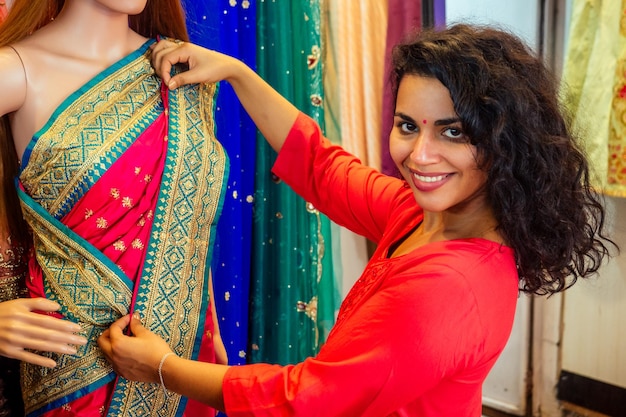Bruna donna indiana scegliendo una nuova tradizione saree in marketneedlewoman designer drappeggio abito in tessuto su un manichino
