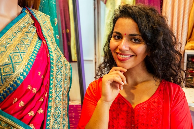 Bruna donna indiana scegliendo una nuova tradizione saree in marketneedlewoman designer drappeggio abito in tessuto su un manichino