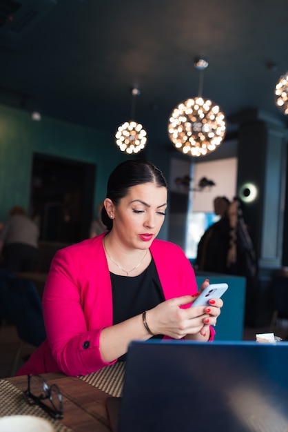 Bruna donna lavora al bar con computer portatile e caffè