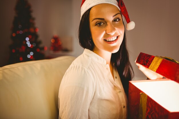 Bruna festivo che apre un regalo d&#39;ardore di natale