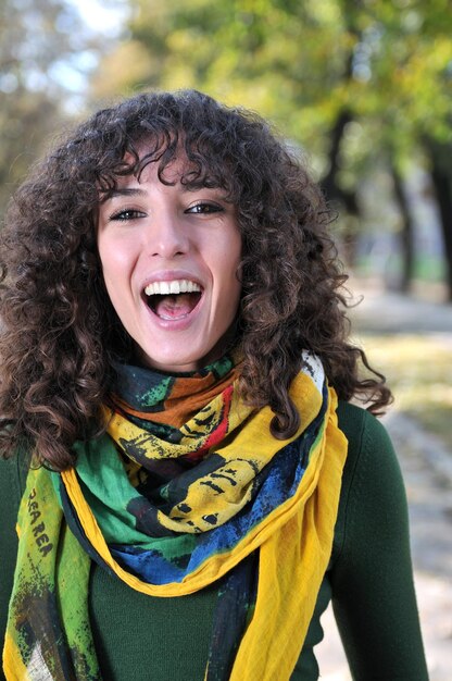 bruna Giovane donna carina con sciarpa colorata sorridente all'aperto in natura