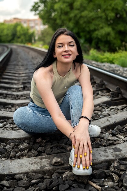 Bruna giovane donna in piedi su un binario ferroviario, viaggio estivo