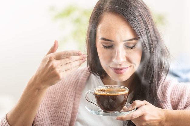 Bruna gode dell'odore del caffè appena fatto in una tazza.