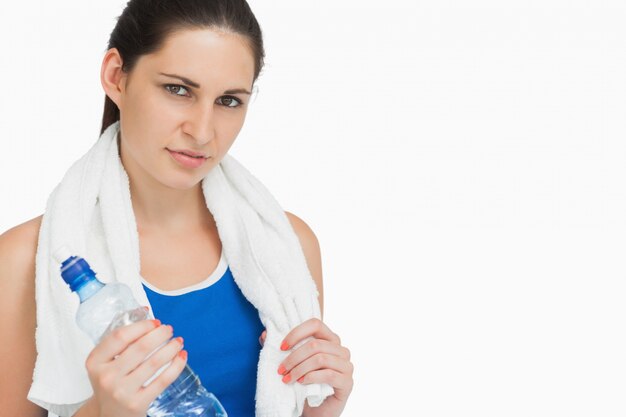 Bruna in abbigliamento sportivo con un asciugamano e una bottiglia