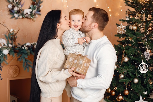 Bruna madre padre e figlio piccolo in piedi vicino all'albero di Natale