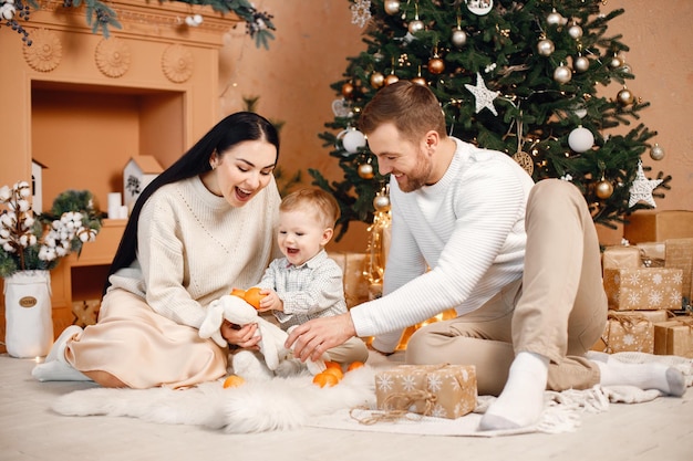 Bruna madre padre e figlio piccolo seduto vicino all'albero di Natale