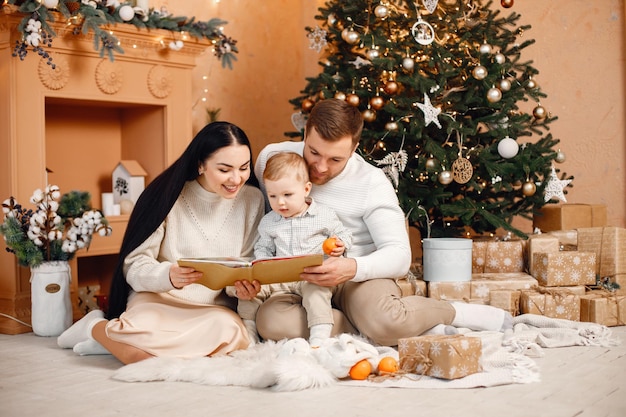 Bruna madre padre e figlio piccolo seduto vicino all'albero di Natale