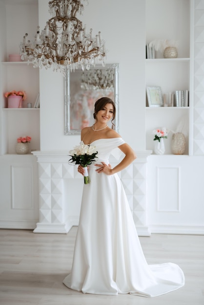 Bruna sposa in un abito da sposa stretto in uno studio luminoso