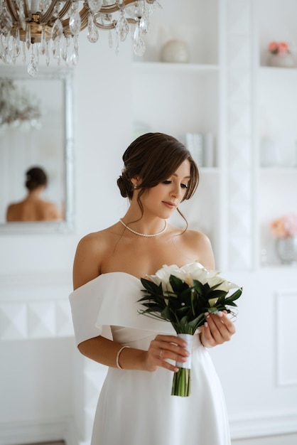 Bruna sposa in un abito da sposa stretto in uno studio luminoso