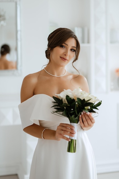 Bruna sposa in un abito da sposa stretto in uno studio luminoso