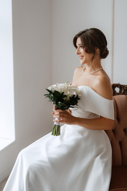 Bruna sposa in un abito da sposa stretto in uno studio luminoso