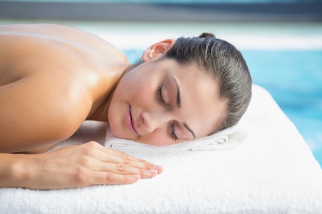 Brunette calmo che si trova sul lettino a bordo piscina di massaggio