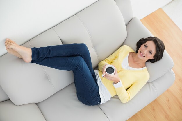 Brunette casuale rilassato in cardigan giallo che tiene una tazza di caffè