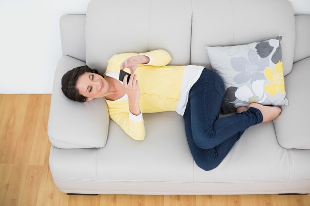 Brunette casuale rilassato in cardigan giallo usando un telefono cellulare