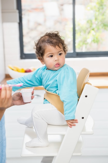 Brunette felice che alimenta il suo bambino in cucina