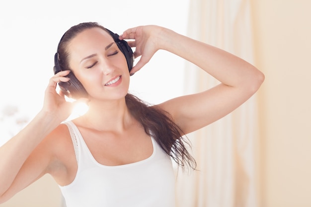 Brunette felice che si siede sul letto che ascolta la musica