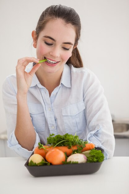 Brunette grazioso che mangia le verdure grezze