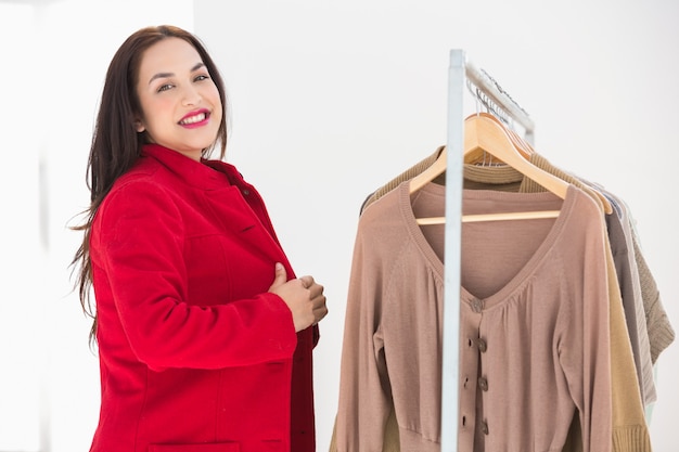 Brunette sorridente che prova il cappotto rosso