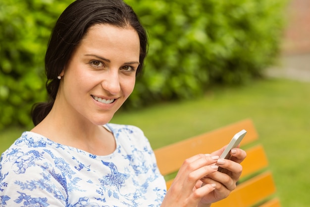 Brunette sorridente usando il suo smartphone