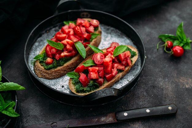 Bruschetta al pesto e pomodori su fondo scuro