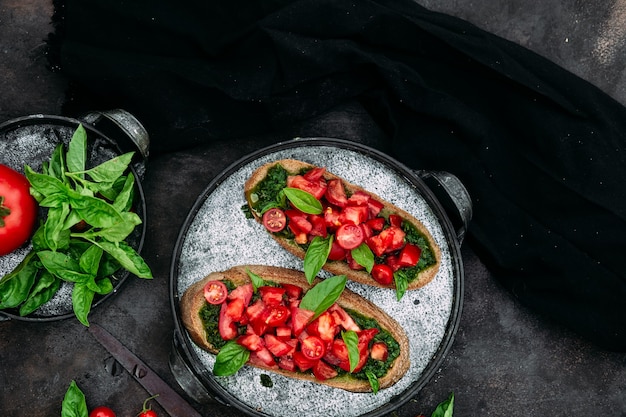 Bruschetta al pesto e pomodori su fondo scuro