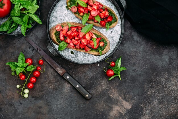 Bruschetta al pesto e pomodori su fondo scuro