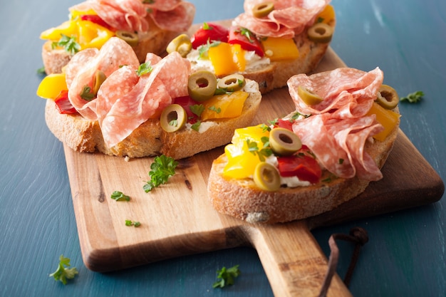 Bruschetta al salame con peperoni arrosto olive formaggio di capra