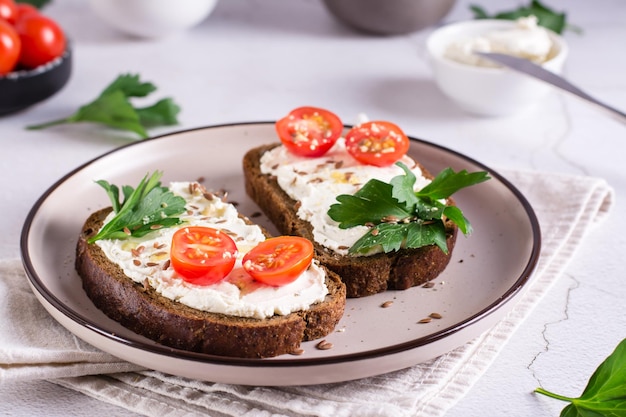 Bruschetta appetitosa con ricotta pomodori semi di lino e prezzemolo su un piatto sul tavolo