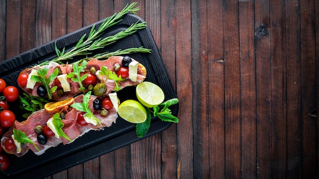 Bruschetta con carne olive erbe aromatiche e parmigiano su pane Snack freddi Cucina italiana su fondo in legno