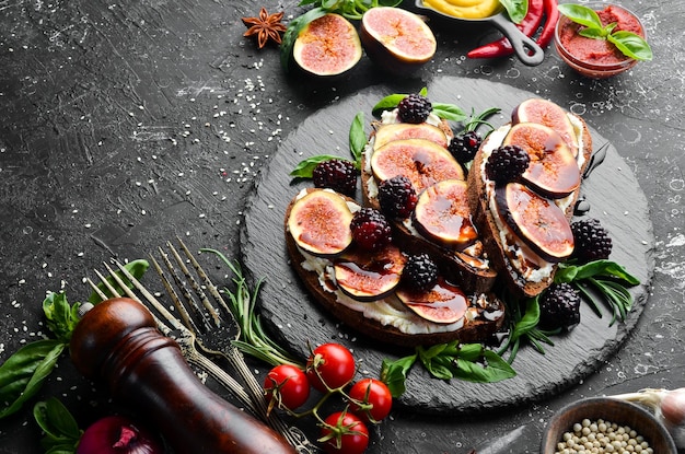 Bruschetta con fichi e more di formaggio Philadelphia su una lastra di pietra nera Vista dall'alto Spazio libero per il testo