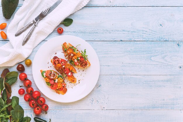 Bruschetta con formaggio, basilico, rucola e pomodorini