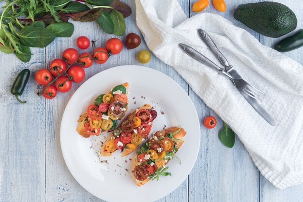 Bruschetta con formaggio, basilico, rucola e pomodorini