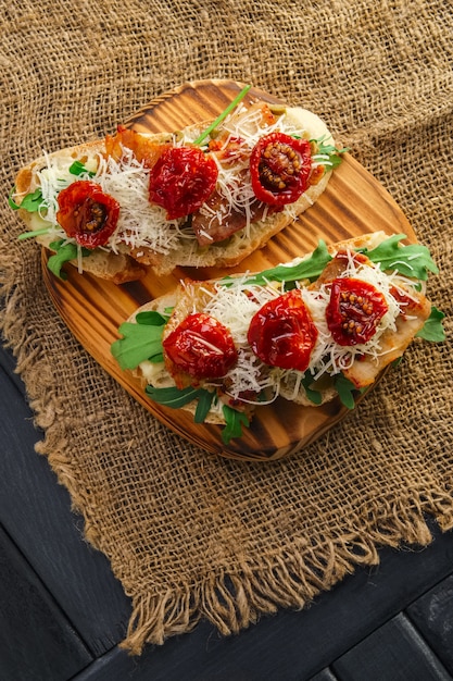 Bruschetta con formaggio, pancetta fritta, olive tritate e pomodori secchi