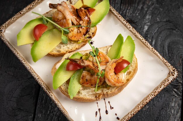 Bruschetta con frutti di mare e verdure su un piatto bianco.