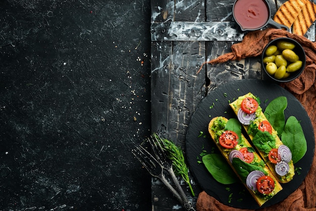 Bruschetta con pasta di avocado pomodori cipolle e spinaci Vista dall'alto Stile rustico